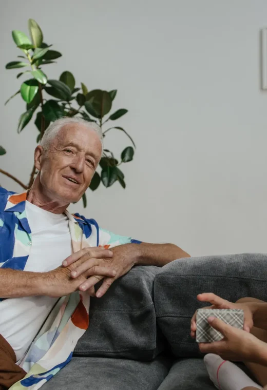 an older gentleman talking to a healthcare worker both sitting on a couch