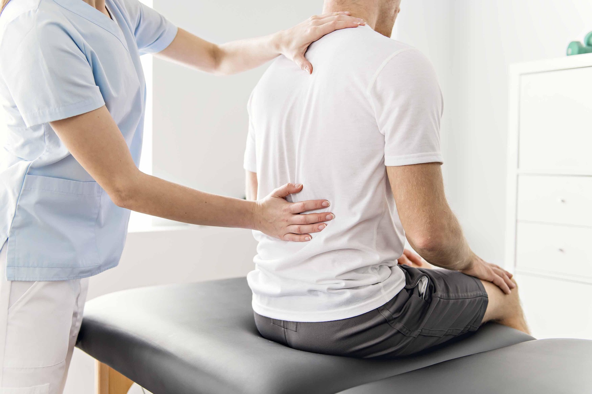 an image of a spinal cord complex care worker examining the spine of a patient