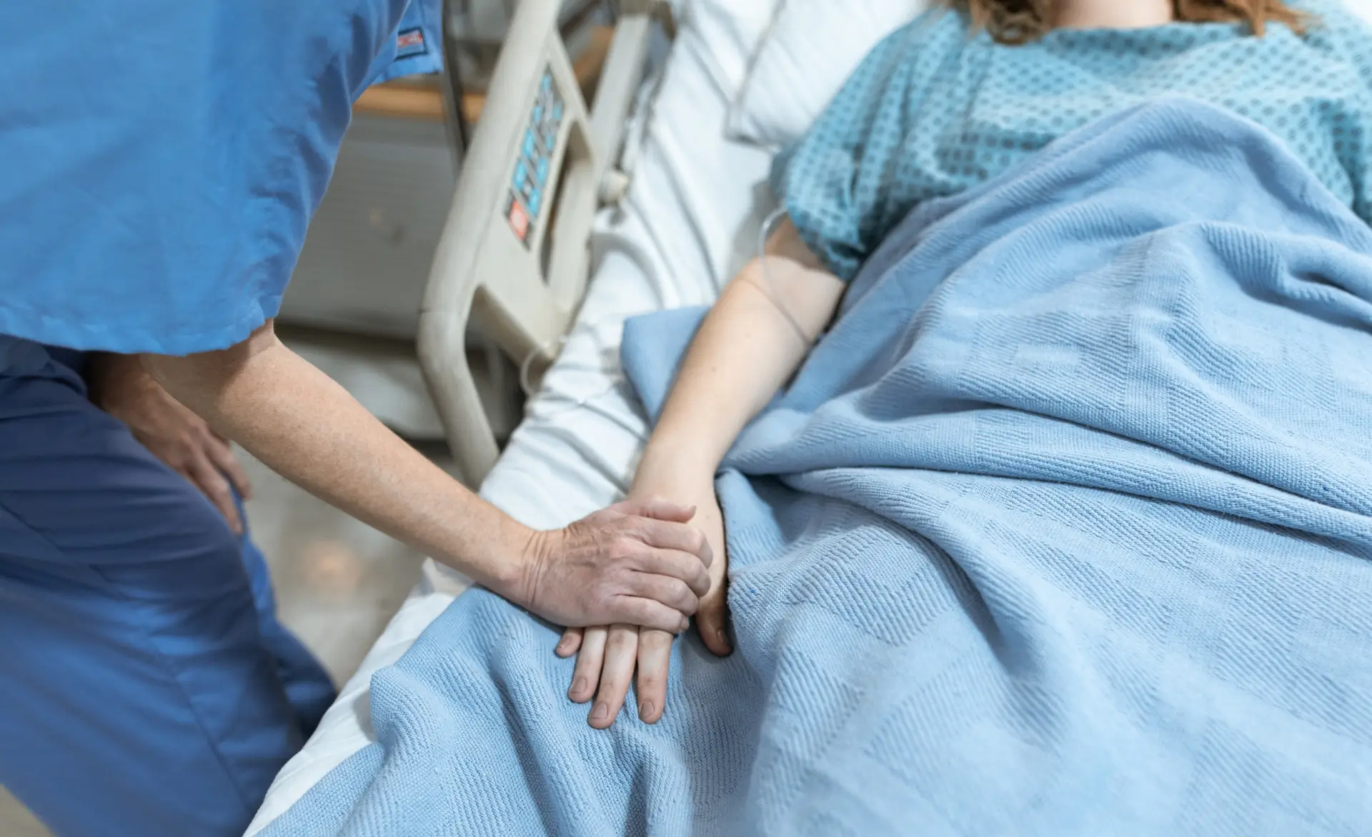 image of a healthcare worker comforting a patient in a hospital bed