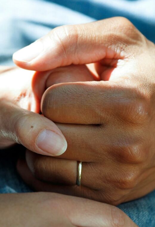 a close up image of the hands of a healthcare professional holding the hand of a patient
