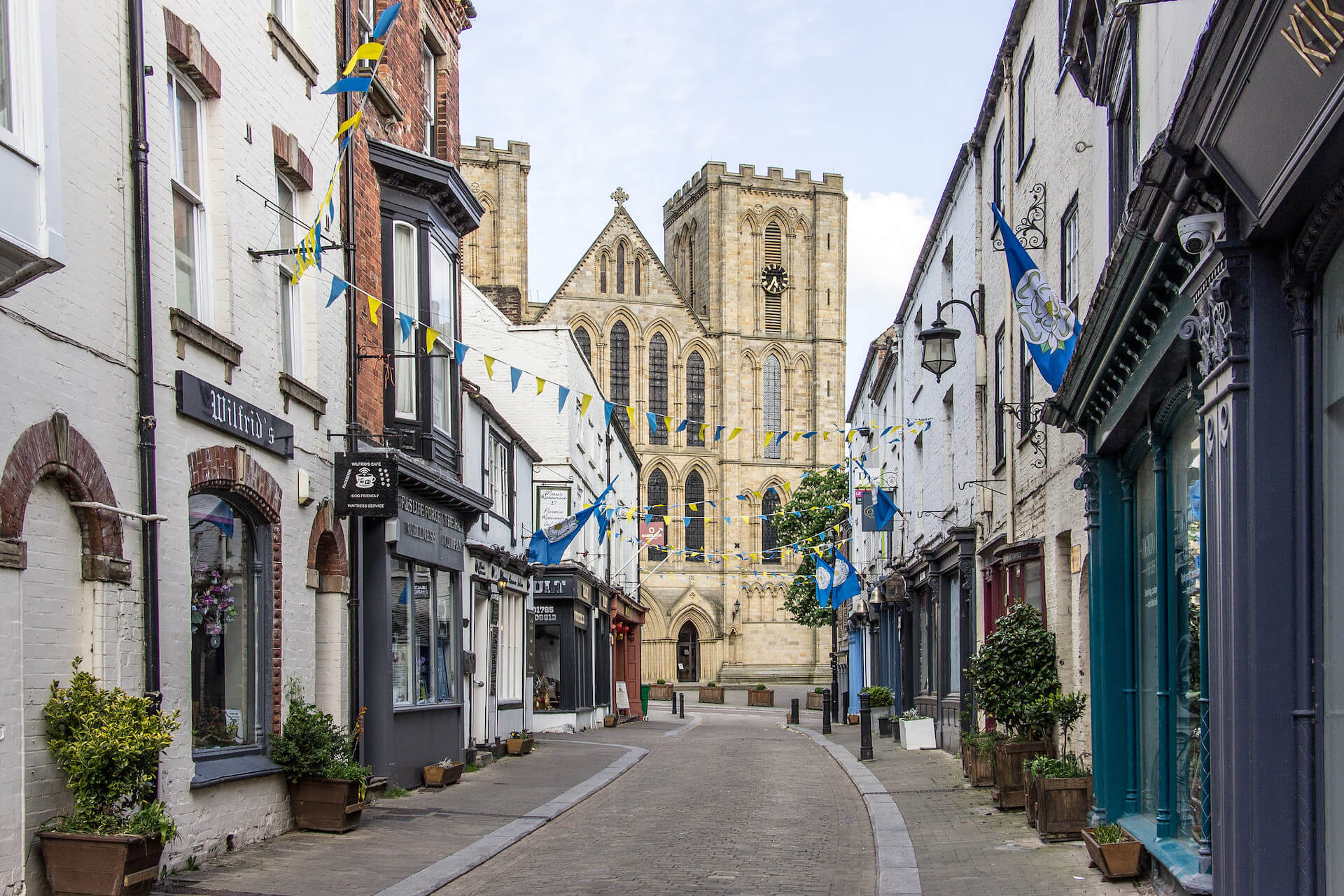 a street view with buildings either side, leading up to Ripon Cathedral