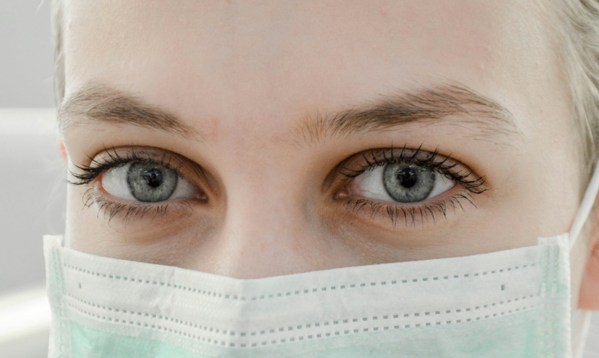 close up images of a nurses' eyes wearing a PPE mask, in an article discussing depression in nursing homes statistics