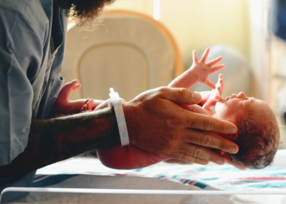 Midwife holding a new born baby representing career paths in midwifery